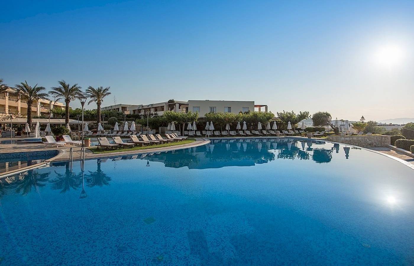 Außenpoolbereich des Cretan Dream Resort & Spa mit Sonnenliegen und Palmen