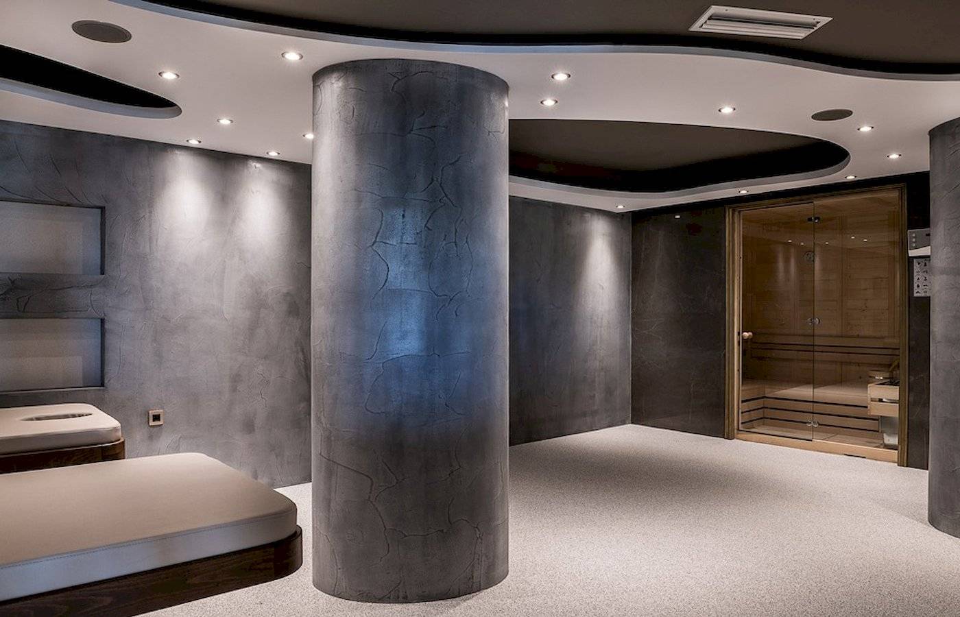 Saunabereich des Cretan Dream Resort & Spa mit grauen Wänden, einem zentralen Säulenelement und einem Holzsauna.
