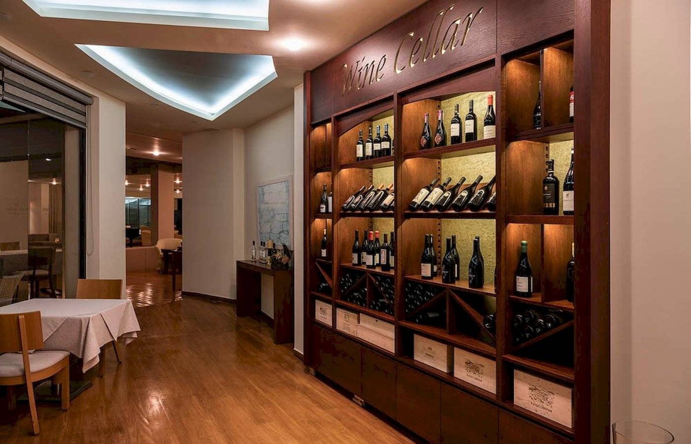 Ein Weinkeller im Cretan Dream Resort & Spa mit Flaschen und einem Tisch.