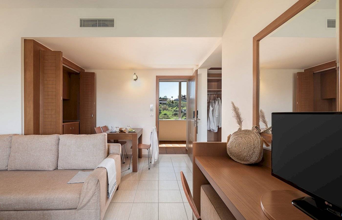Innenansicht des Cretan Dream Resort & Spa mit Wohnzimmer, Couch, Tisch und Fernseher.