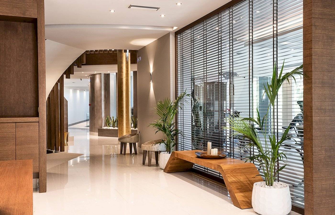 Innenbereich des Cretan Dream Resort & Spa mit Holzmöbeln, Pflanzen und einer Wendeltreppe.