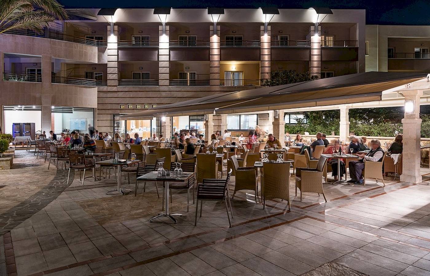 Ein Hotelrestaurant bei Nacht mit Gästen, die an Tischen sitzen und essen.