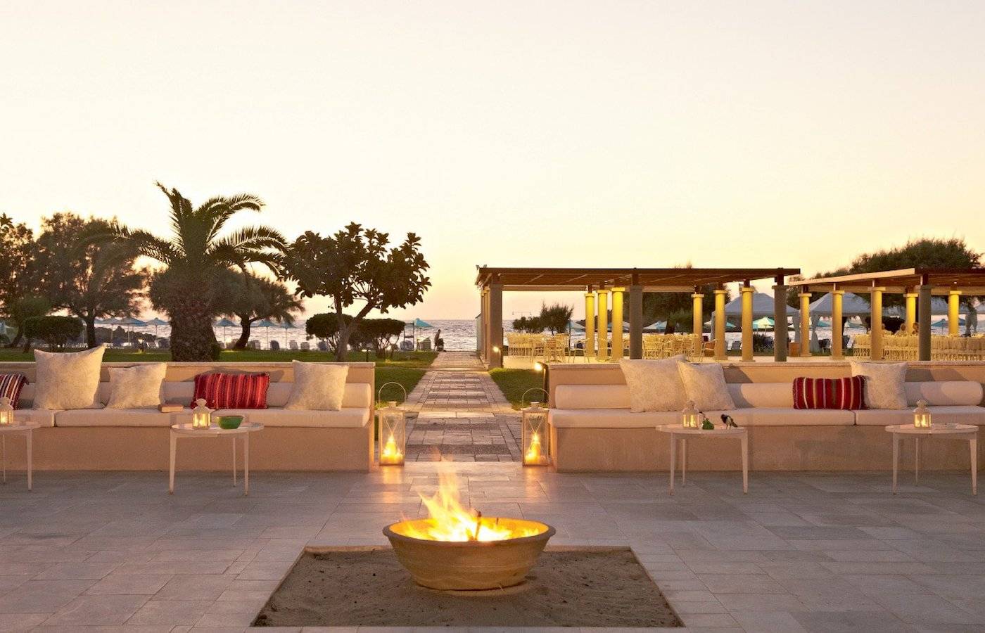 Außenloungebereich des Grecotel Meli Palace mit Sofas, Feuerstelle und Meerblick