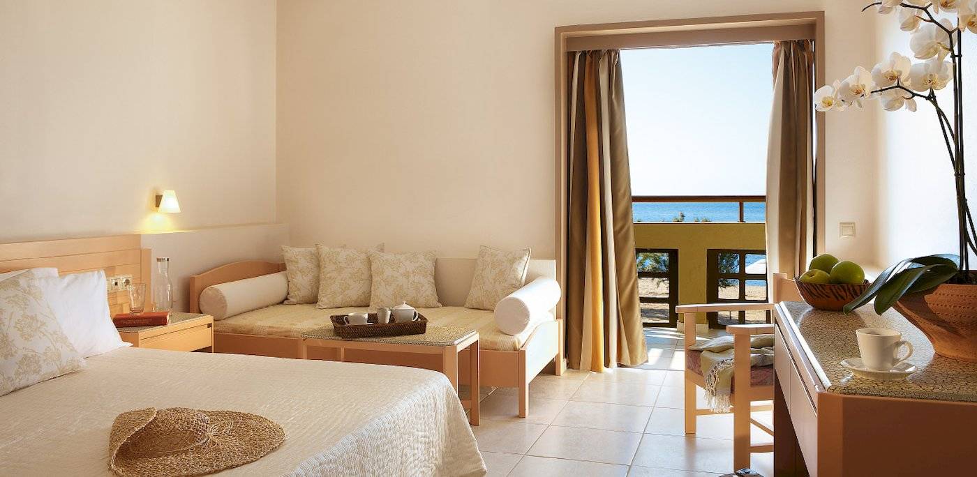 Hotelzimmer im Grecotel Meli Palace mit einem Sofabett, einem Schreibtisch und einem Ausblick auf das Meer.