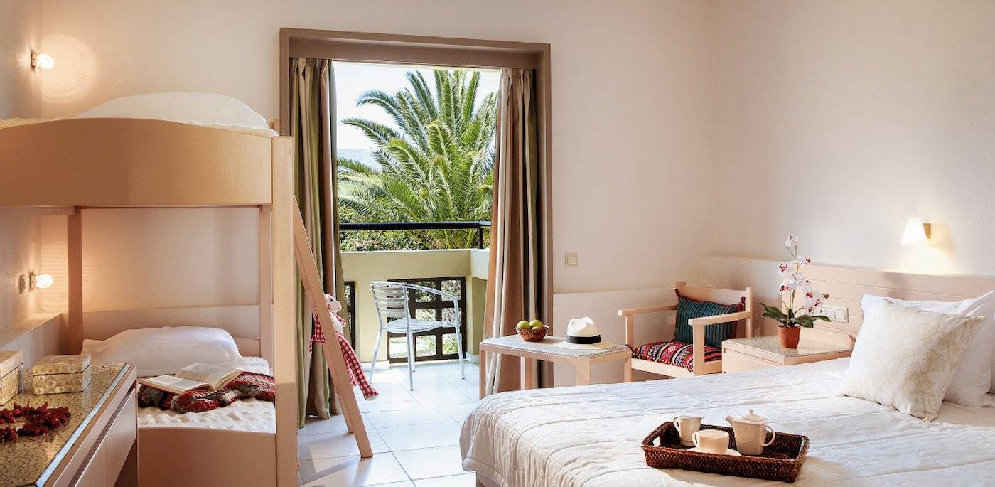 Doppelzimmer im Grecotel Meli Palace mit Blick auf eine Terrasse und eine Palme