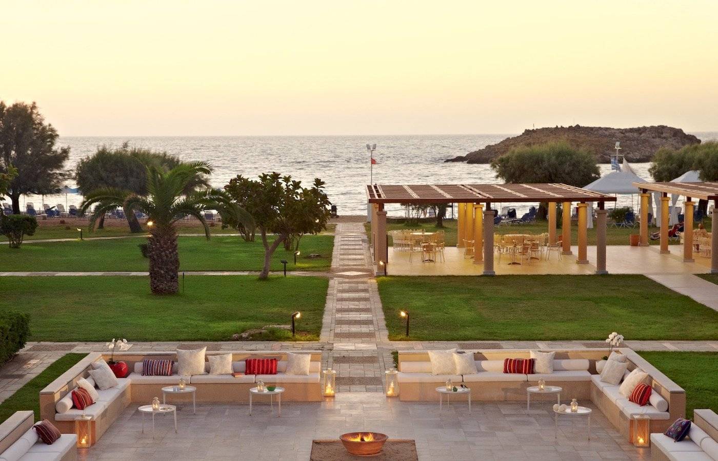 Außenbereich des Grecotel Meli Palace mit Blick auf das Meer bei Sonnenuntergang.