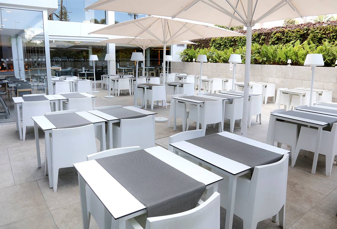 Außenbereich des LABRANDA Bronze Playa Hotels mit weißen Tischen und Stühlen unter Schirmen.