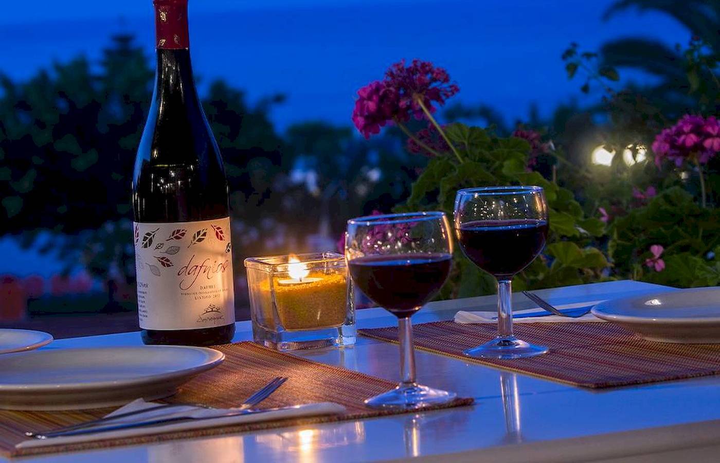 Abendessen bei Kerzenlicht im Chrissi Amoudia mit Weinflasche, zwei Gläsern und Kerze in einem Glas.