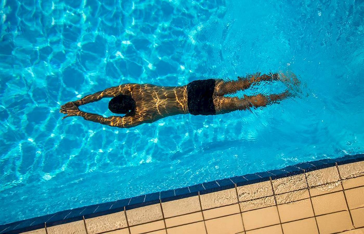 Ein Mann schwimmt im Pool von Chrissi Amoudia Hotel.