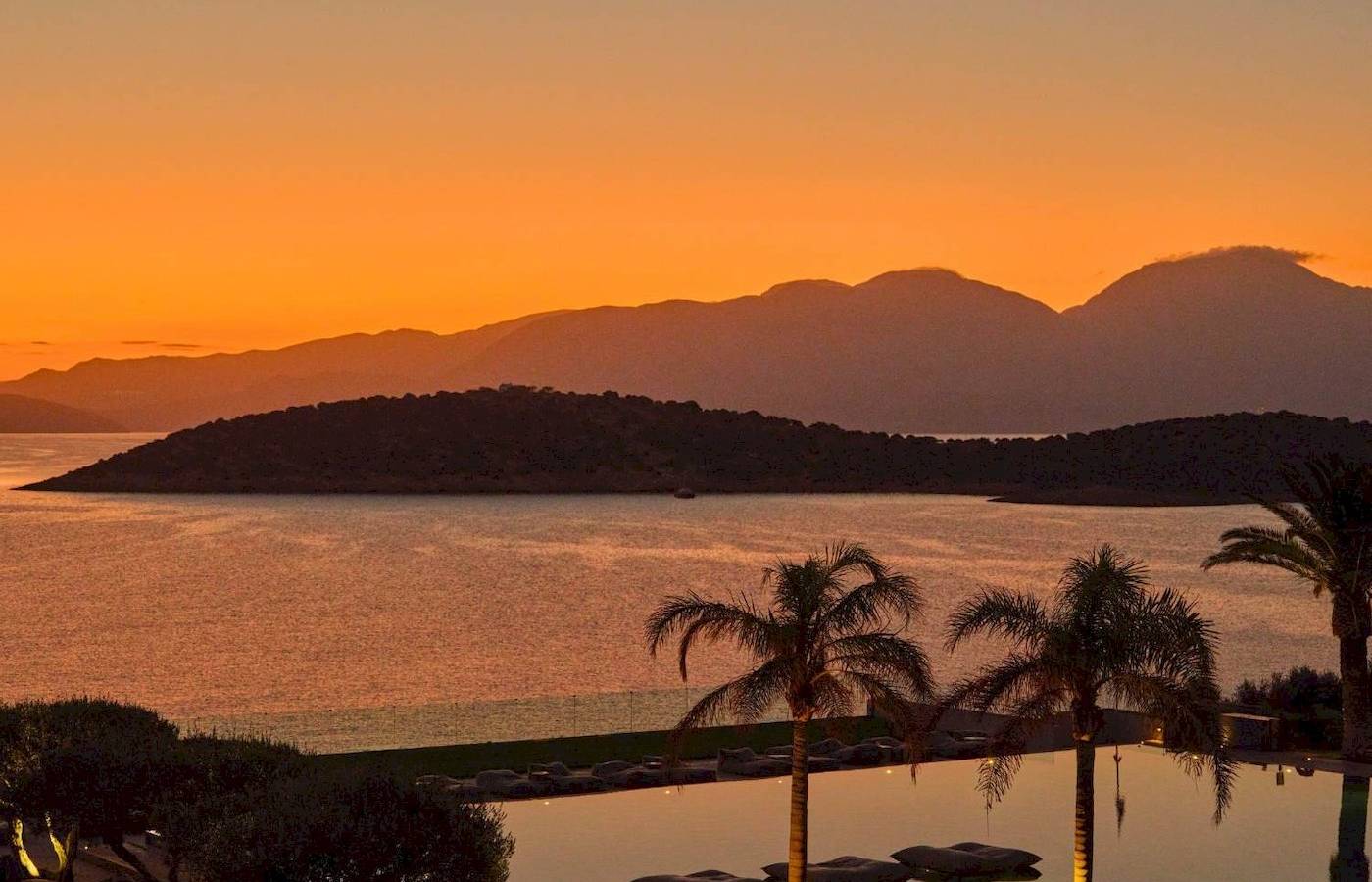 Abendlicher Sonnenuntergang im Hotel Minos Palace Hotel & Suites mit Blick auf das Meer und die Berge.