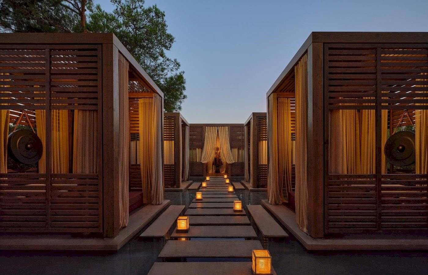 Lounge-Bereich des Minos Palace Hotel & Suites mit Holzhütten und beleuchteten Wegen.