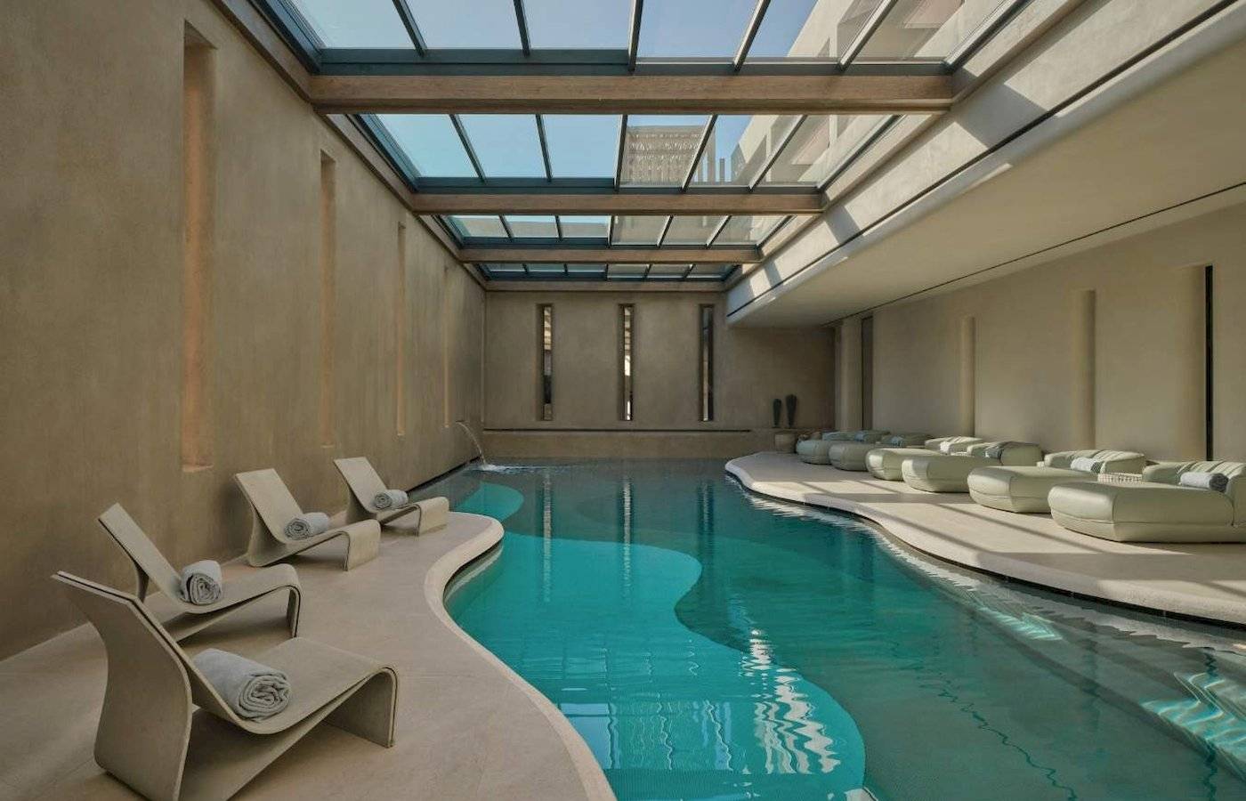 Innenpool des Minos Palace Hotel & Suites mit Lounge-Sesseln und einem Glasdach.