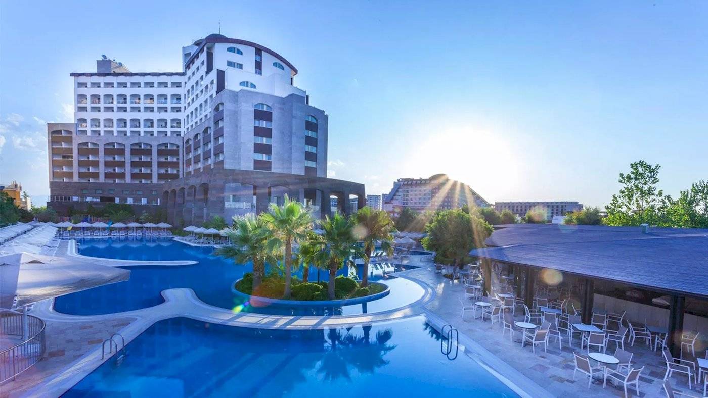 Das Melas Lara Hotel zeigt seinen Swimmingpool und eine Terrasse mit Tischen und Stühlen im Freien.