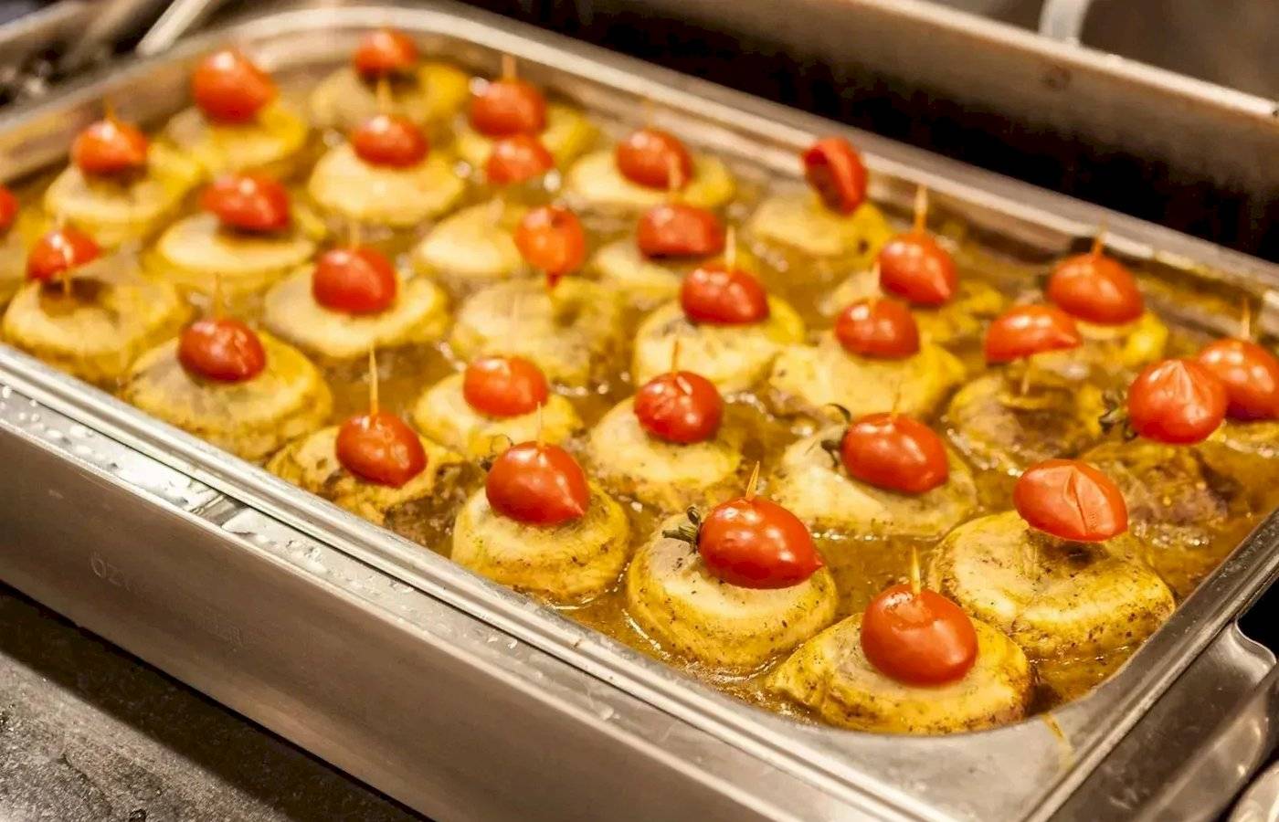 Ein Tablett mit gebackenen Kartoffeln, die mit Tomaten und Essiggurken auf Spießen serviert werden, im Melas Lara Hotel.