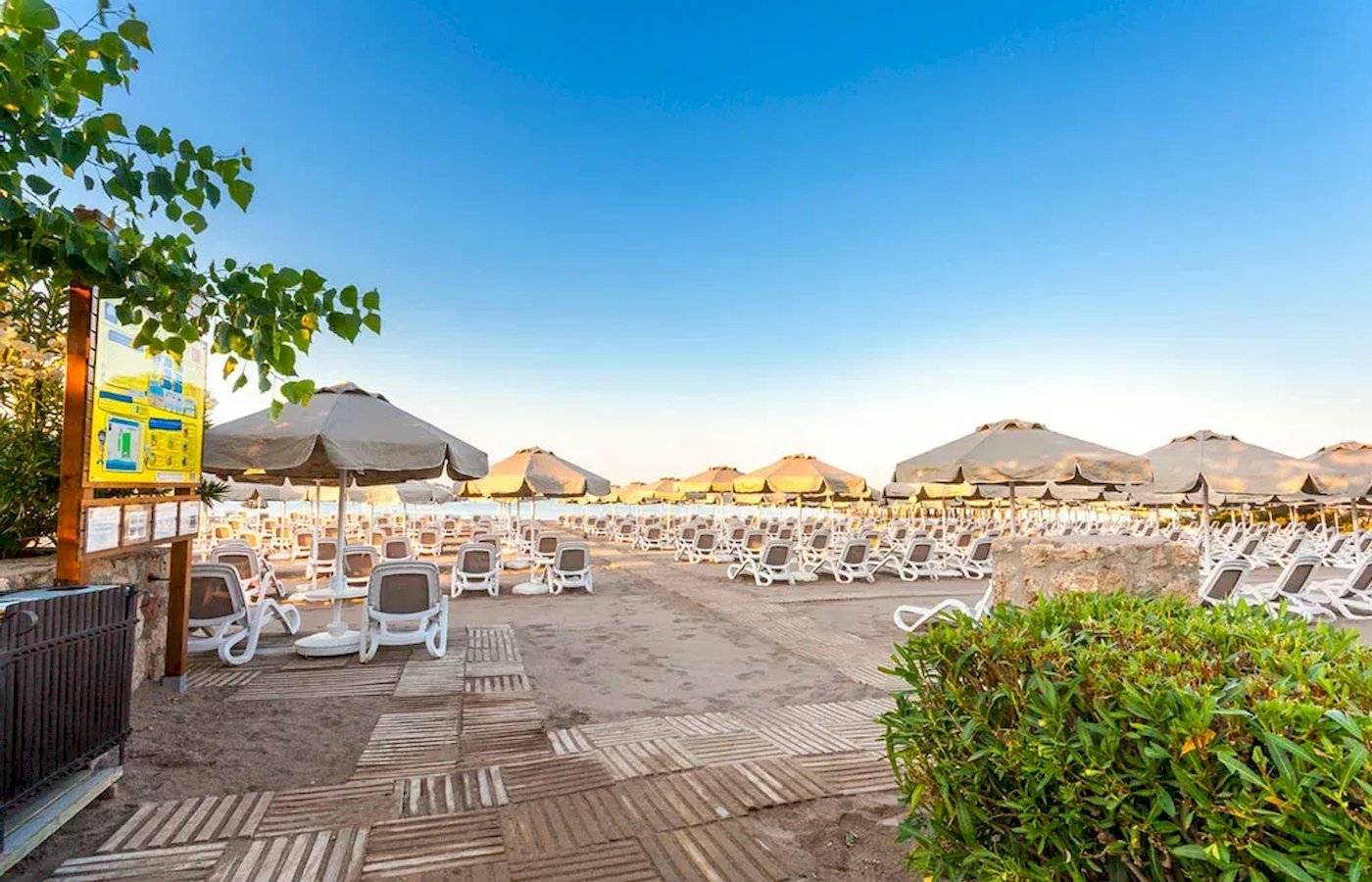 Strand des Melas Lara Hotels mit vielen Sonnenliegen und Sonnenschirmen.