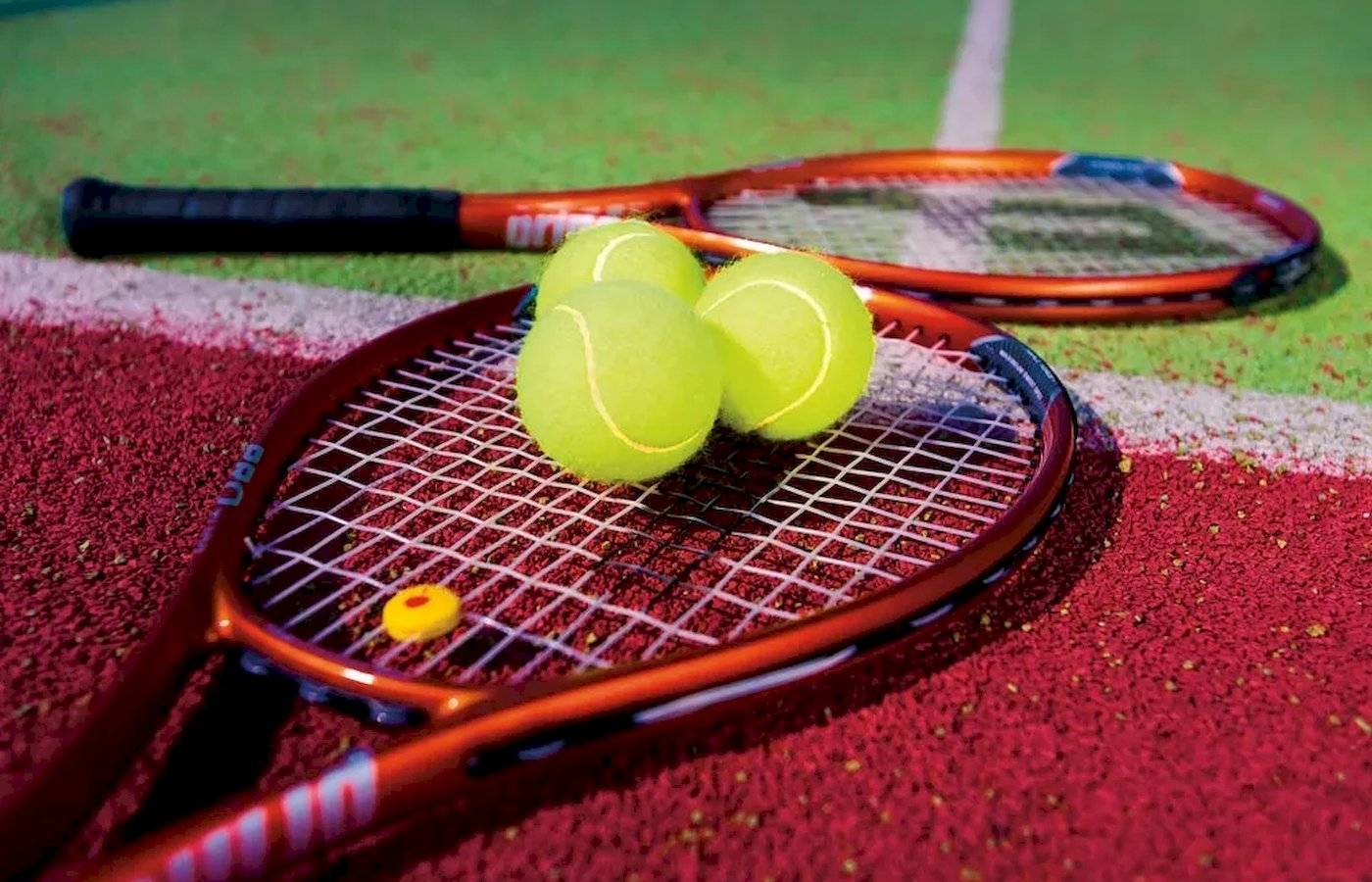 Tennisschläger und Bälle auf einem roten Tennisplatz