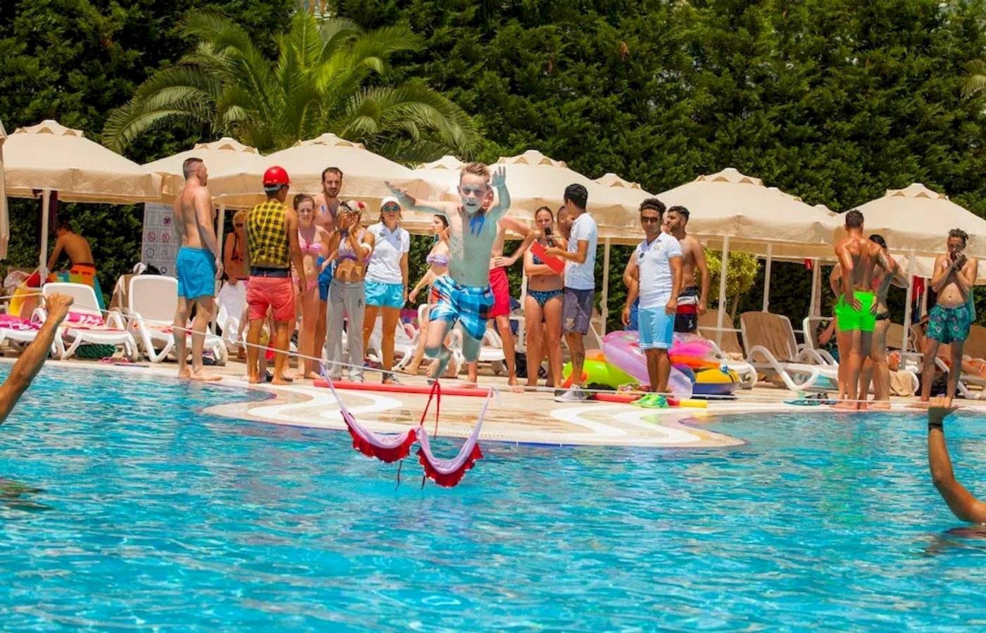Im Melas Lara Hotel springen Kinder über Hüpfschlingen im Schwimmbad.