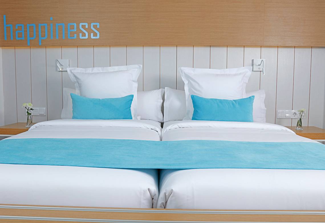 Ein Doppelbett mit weißen Laken, blauen Kissen und einem blauen Bettlaken im LABRANDA Bronze Playa Hotel.