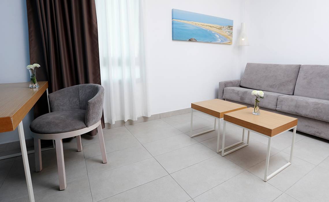Das Hotelzimmer des Labranda Bronze Playa mit Sofa, Beistelltischen und Tisch mit Blumenvase.