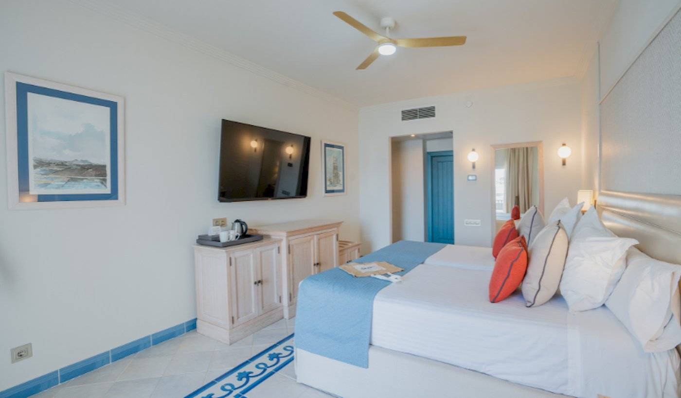 Schlafzimmer im LIVVO Volcan Lanzarote Hotel mit Doppelbett, Fernseher und Nachttisch.