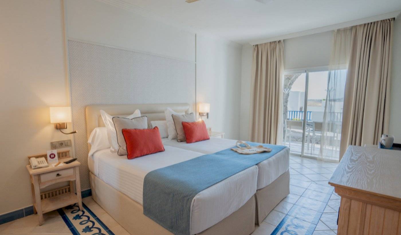 Doppelzimmer mit Meerblick im LIVVO Volcan Lanzarote Hotel, mit zwei Betten, einem Schreibtisch und einer Terrasse.