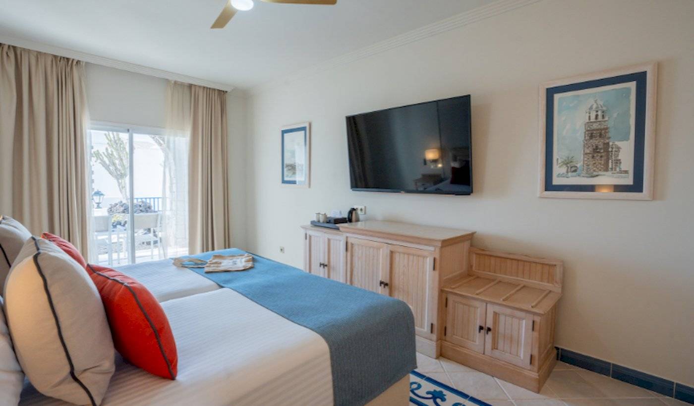 Zimmer im LIVVO Volcan Lanzarote Hotel mit Doppelbett, Fernseher und Balkon.