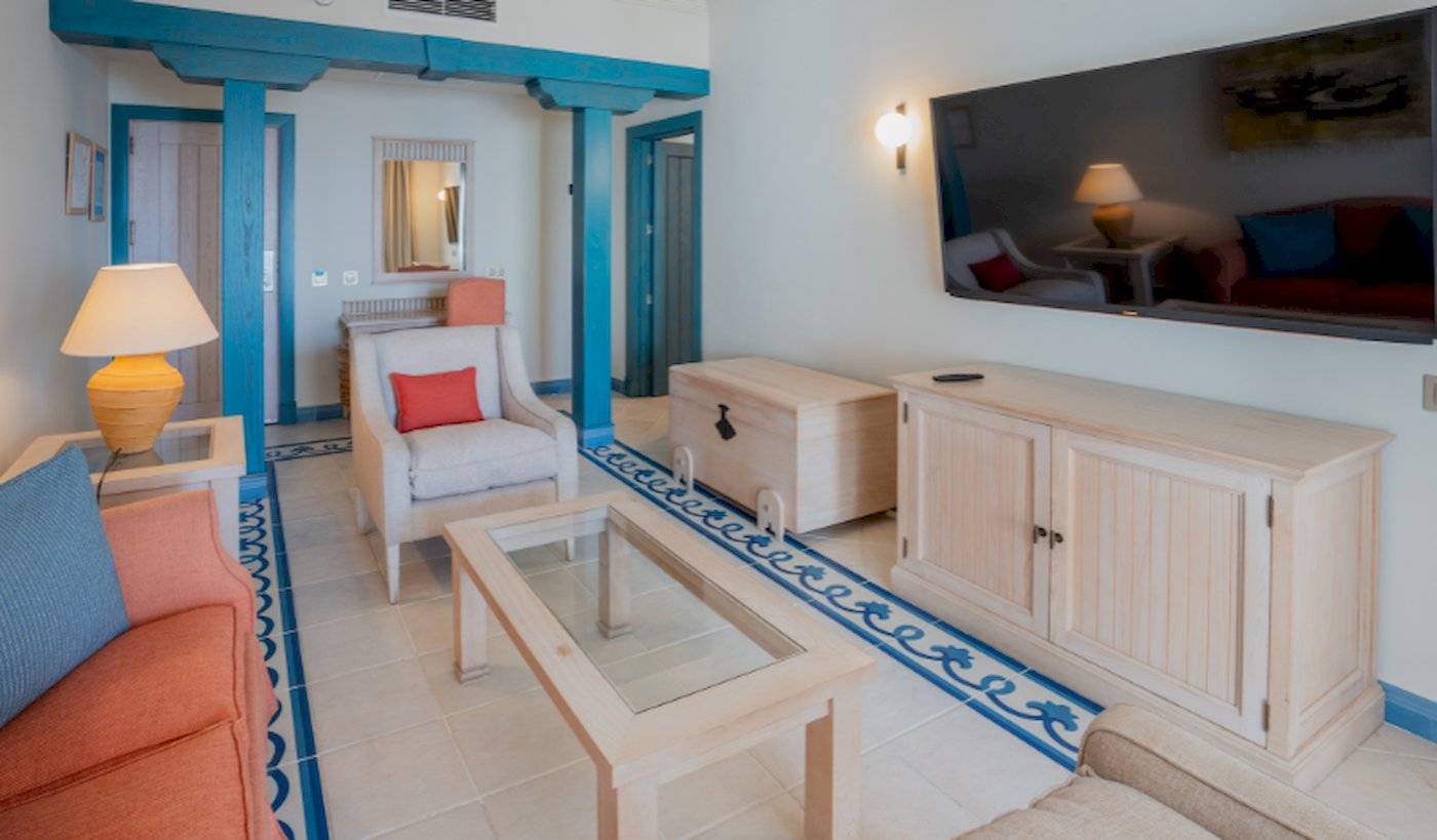 Wohnzimmer-Innenansicht im LIVVO Volcan Lanzarote Hotel mit Sofa, Couchtisch, Fernseher und Lampe.