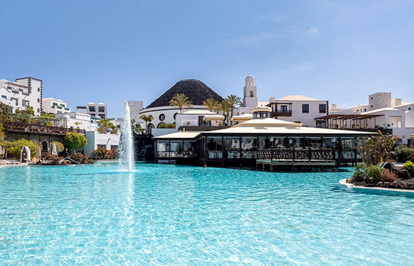 Außenpool des LIVVO Volcan Lanzarote Hotels mit weißen Gebäuden im Hintergrund.