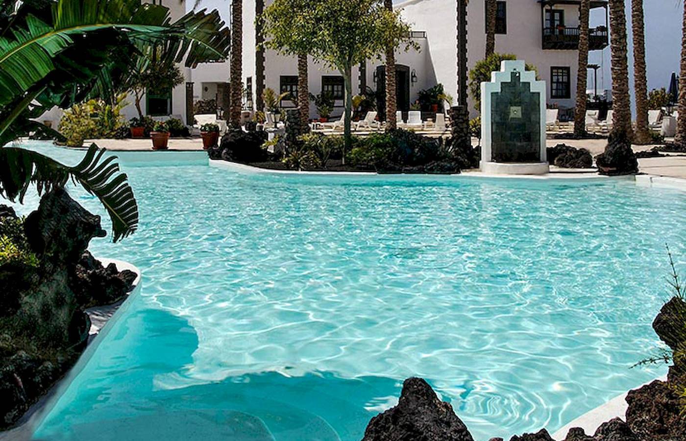 Außenpoolbereich des LIVVO Volcan Lanzarote Hotels mit Palmen und weißen Gebäuden