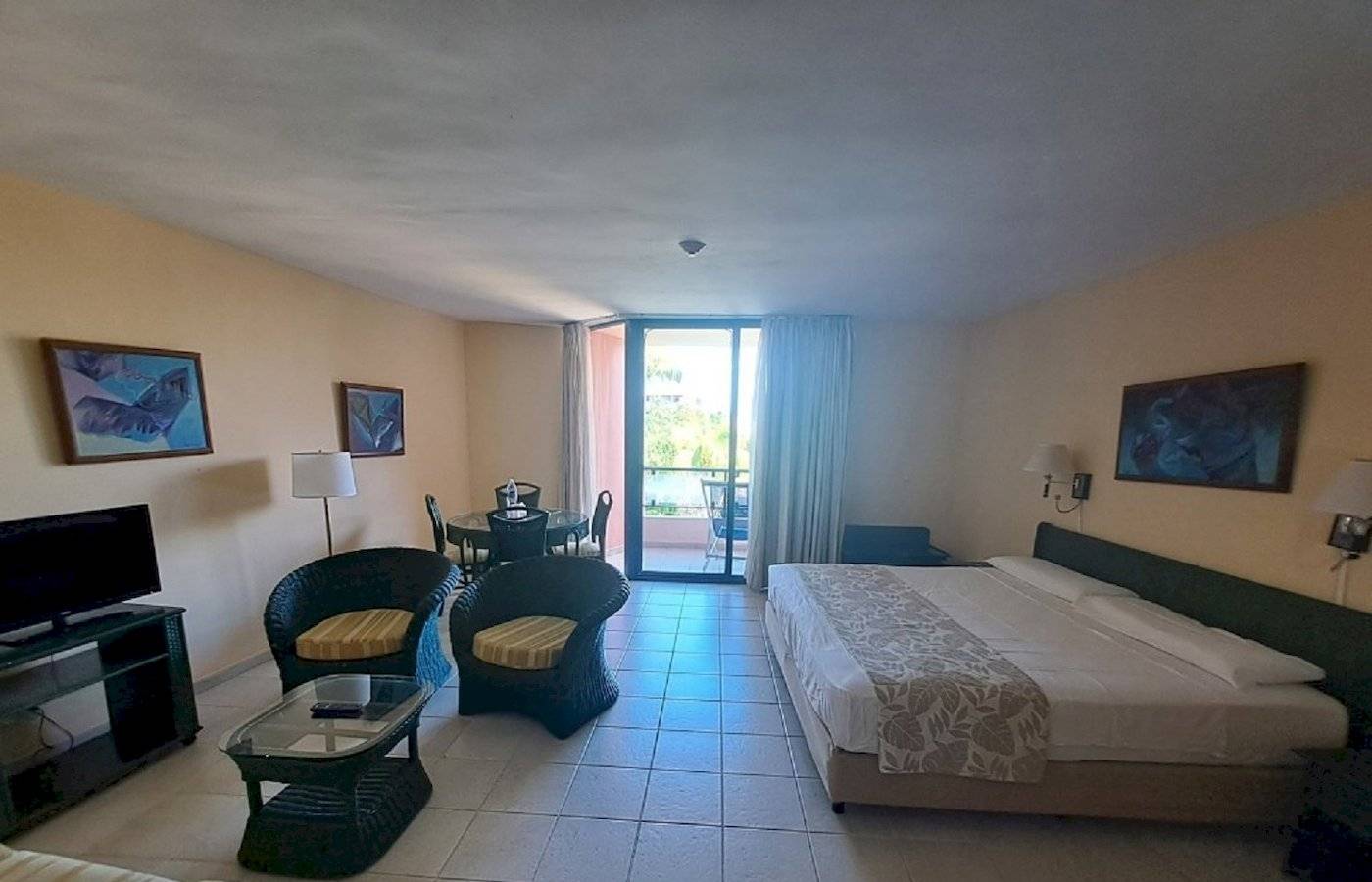 Zimmer im Muthu Playa Varadero Hotel mit Bett, Tisch, Stühlen und Fernseher.