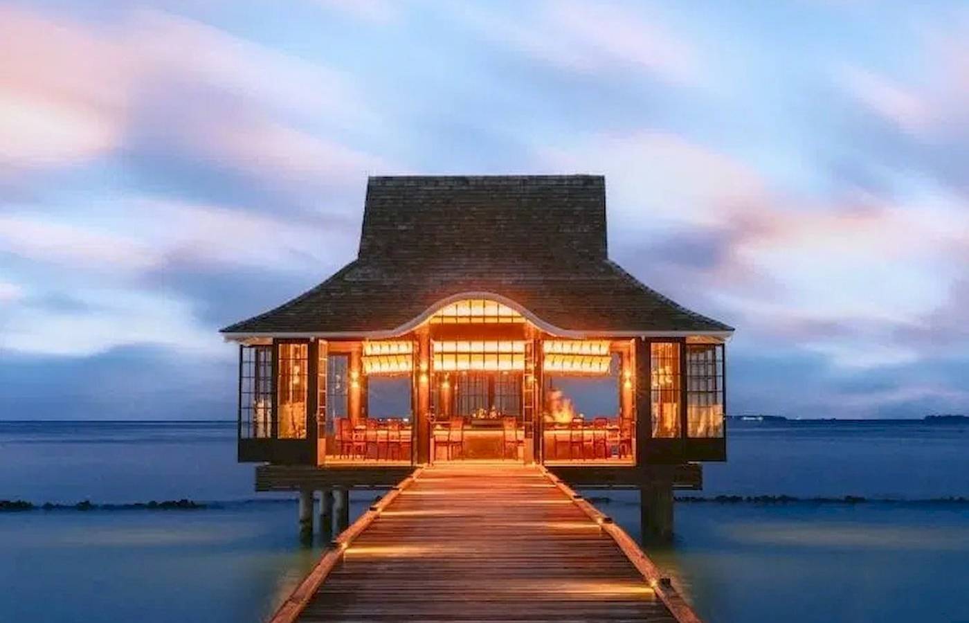 Nova Maldives Resort bei Nacht mit beleuchtetem Steg und illuminiertem Eingang