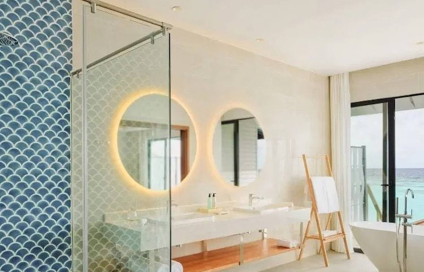 Badezimmer im Nova Maldives Hotel mit doppeltem Waschbecken und Badewanne mit Meerblick.