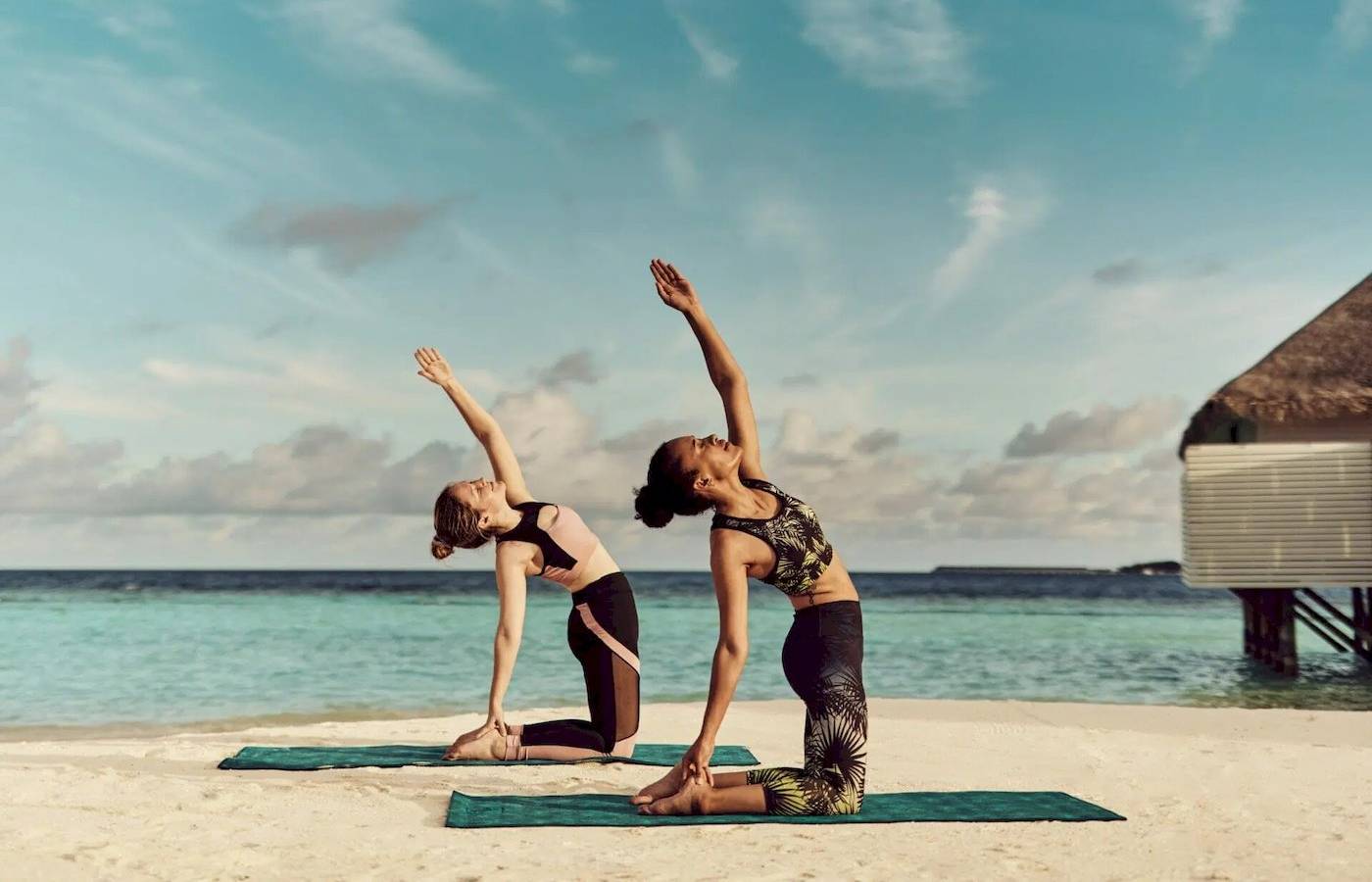 Zwei Frauen machen Yoga auf dem Strand im Nova Maldives.