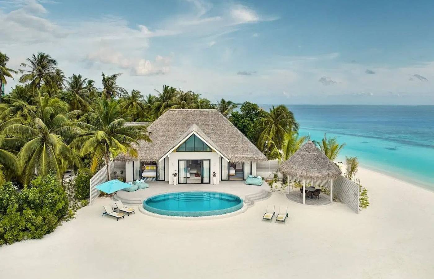 Luftaufnahme der Nova Maldives Villa mit Pool und Sonnenliegen auf dem Strand.