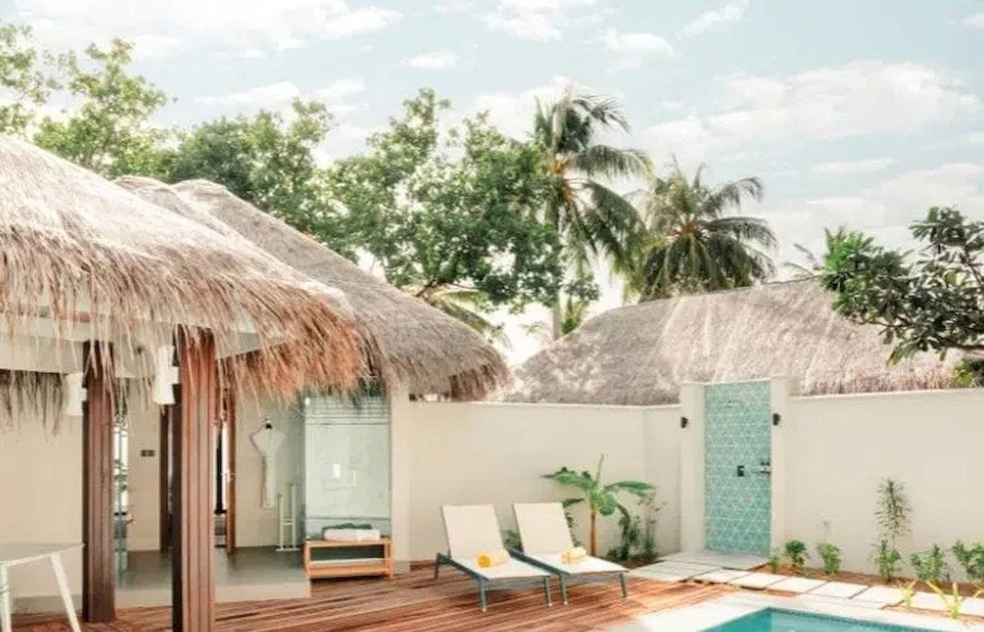 Privatpool in der Villa des Nova Maldives Hotels mit Sonnenliegen und Tisch.