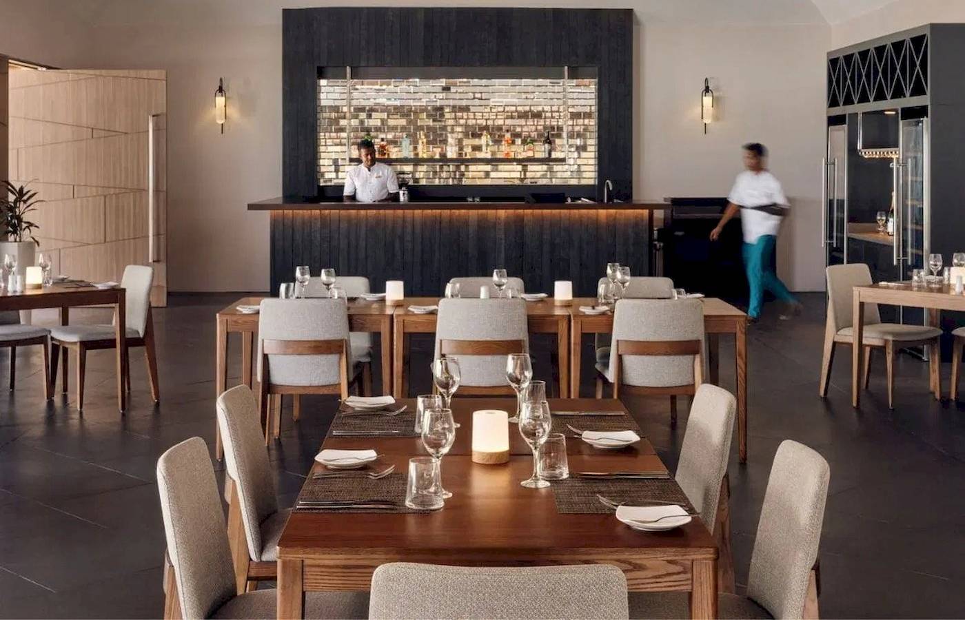 Restaurant-Innenbereich des Nova Maldives mit Tischen, Stühlen und Bar.