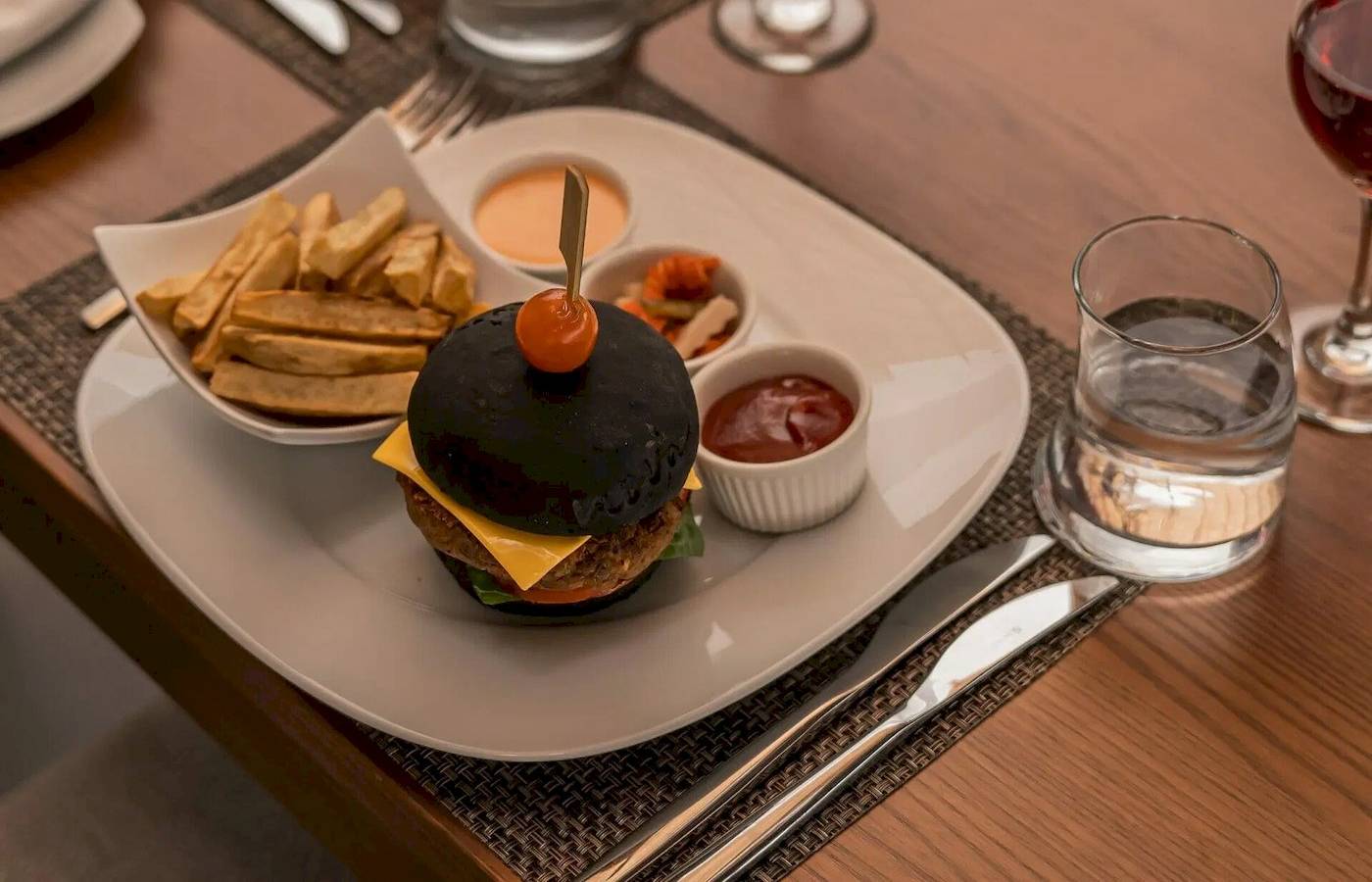 Nova Maldives Hotel Essen auf Tisch mit Burger, Pommes, Glas Wasser und Wein