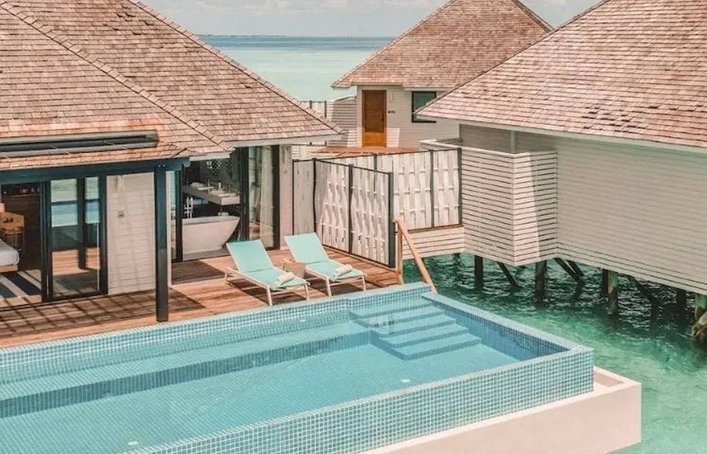 Nova Maldives Hotel Pool-Villa mit zwei Liegen und Badewanne am Meer.