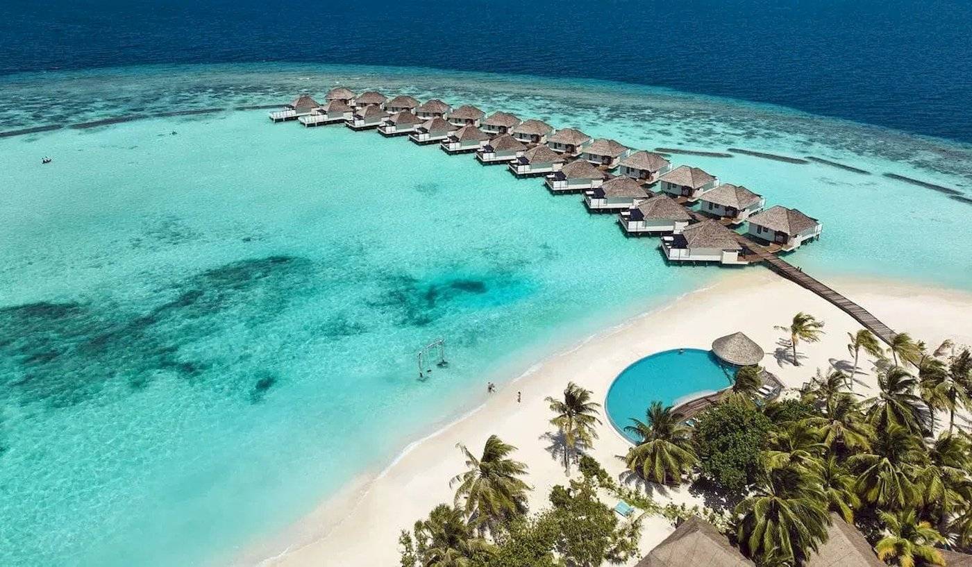 Luftaufnahme des Nova Maldives Hotels mit Wasservillen und Swimmingpool am Strand