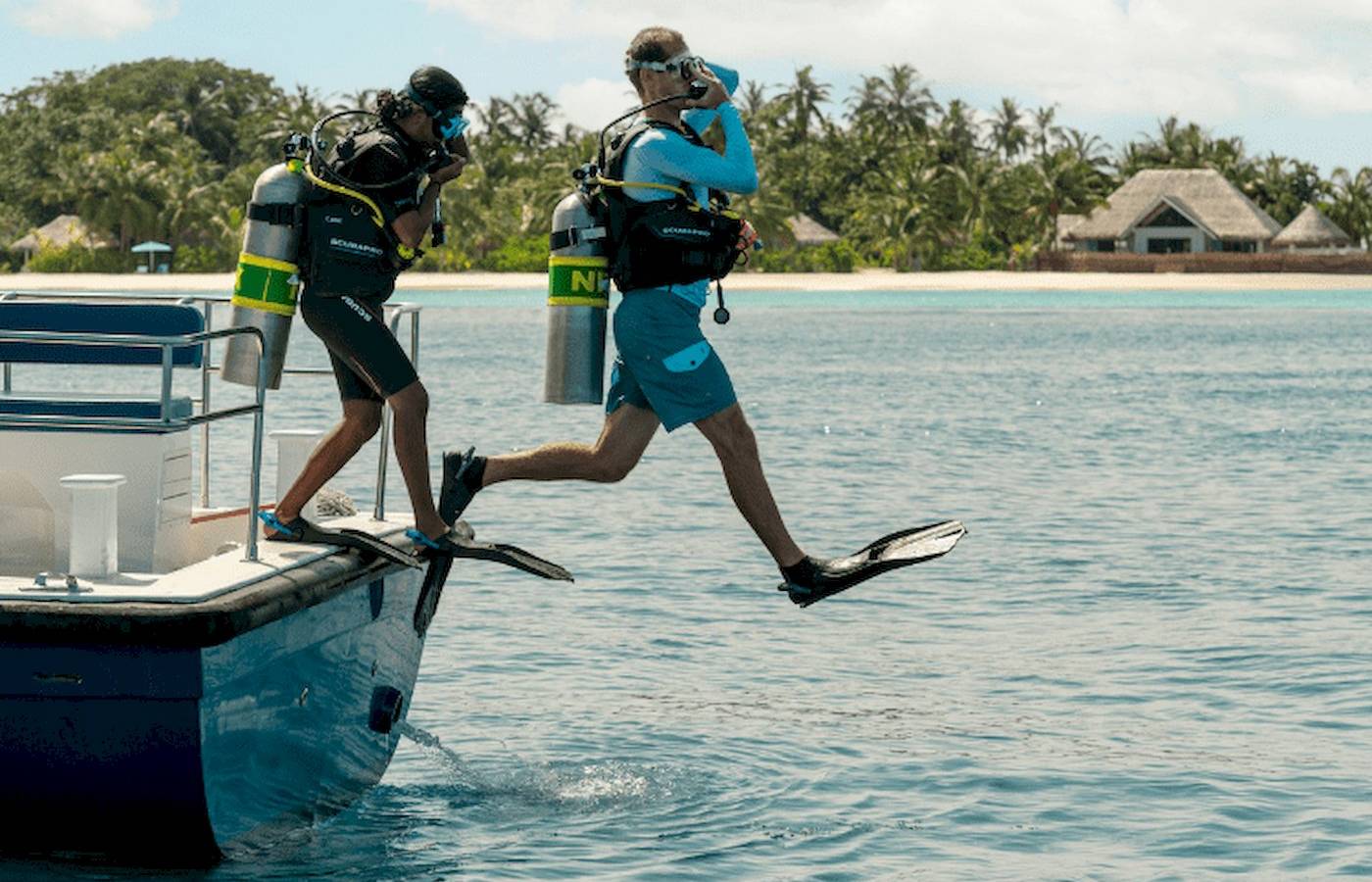 Scuba-Taucher betreten das Meer vor dem Nova Maldives Hotel.
