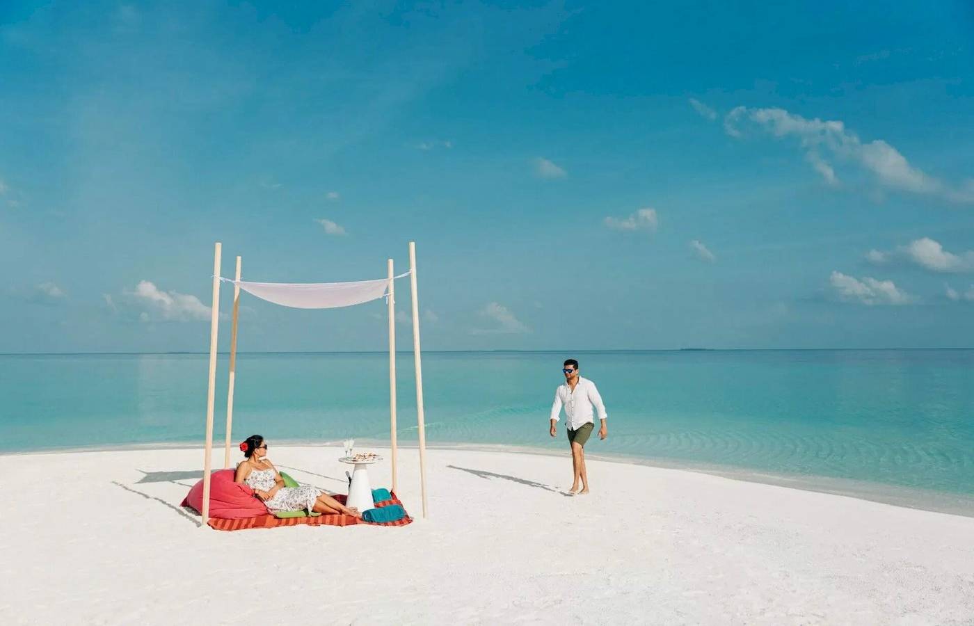 Nova Maldives Hotel Strand Sitzgelegenheit mit Sonnenschirm und Meer im Hintergrund.