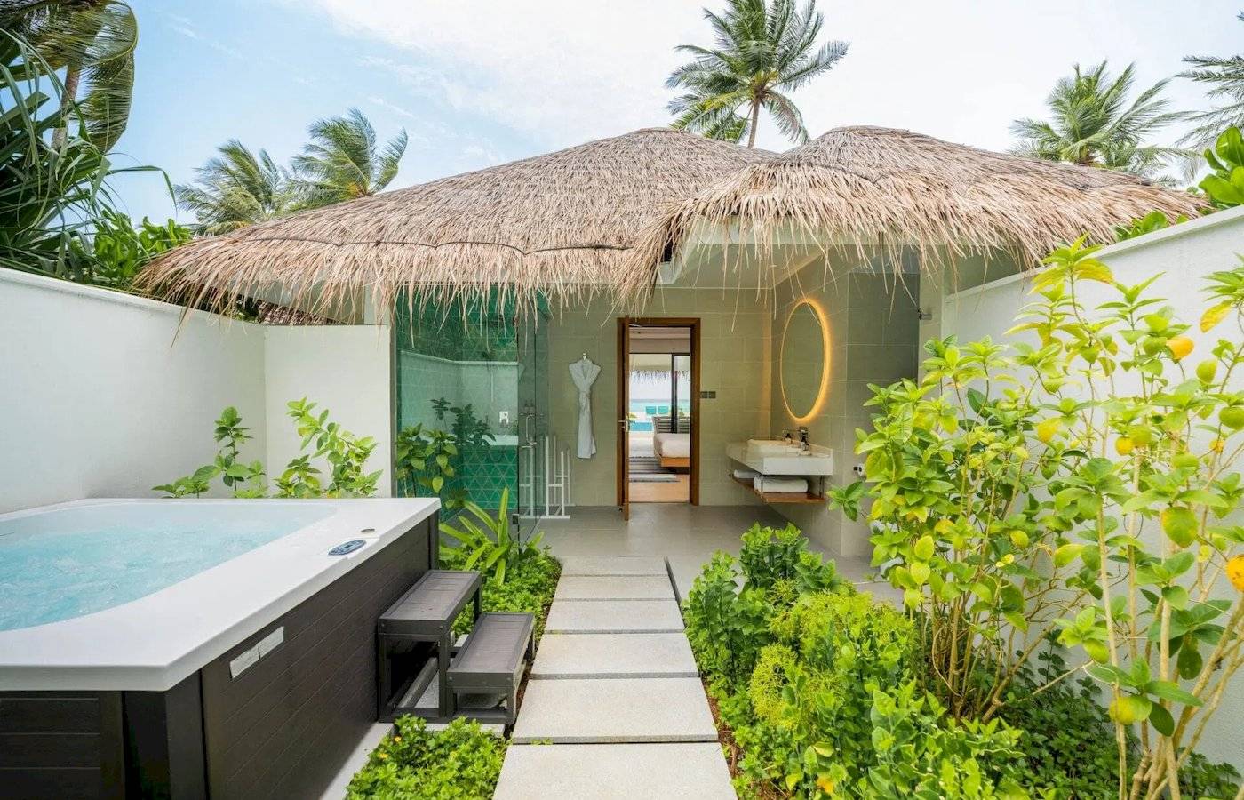 Außenbereich des Nova Maldives Hotels mit einer kleinen Hütte und einem Jacuzzi