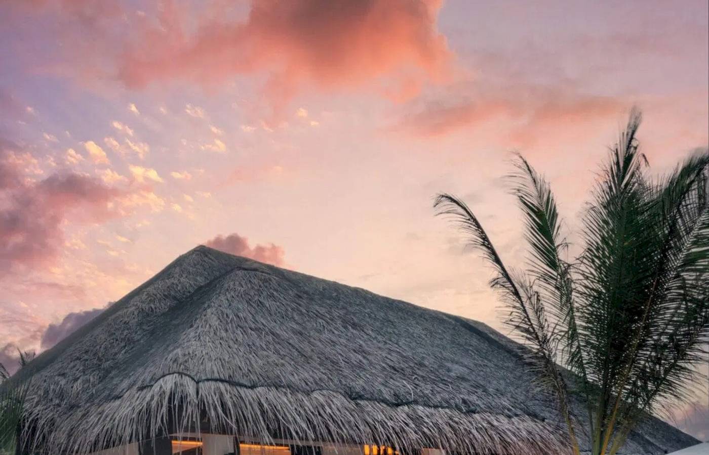 Außenansicht der Nova Maldives Grill House bei Sonnenuntergang mit beleuchteten Eingängen.