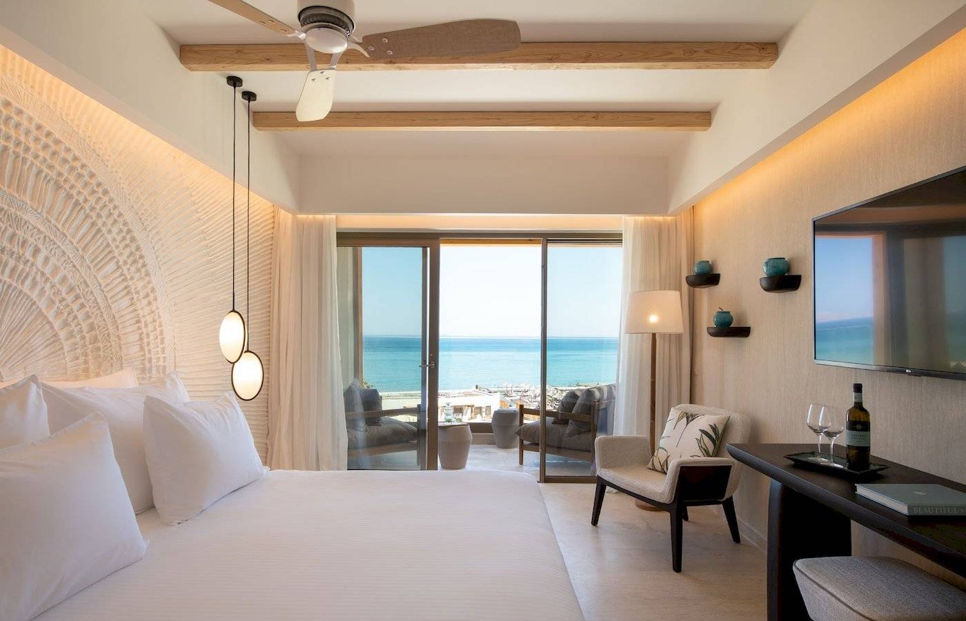 Mitsis Selection Rinela Hotel Suite mit Meerblick, Bett, Möbeln, Lampen und Fernseher.