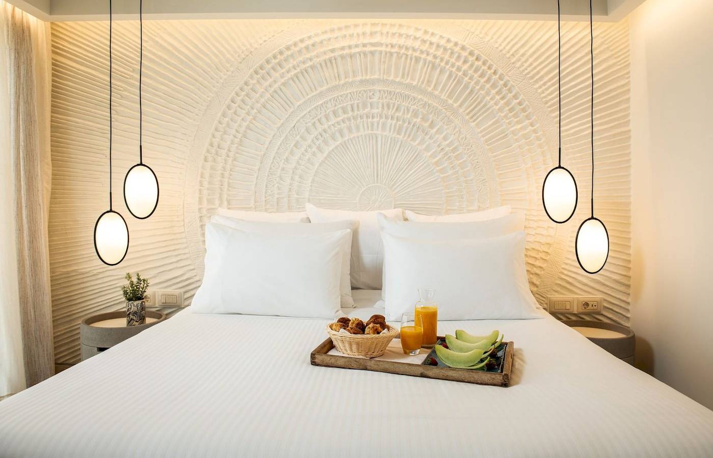 Fruehstueckskorb mit Obst auf einem Bett im Mitsis Selection Rinela Hotel.