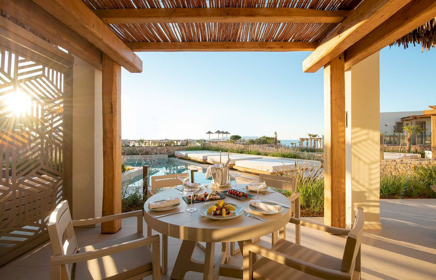 Terrasse im Mitsis Selection Rinela Hotel mit Aussicht auf den Pool und das Meer.