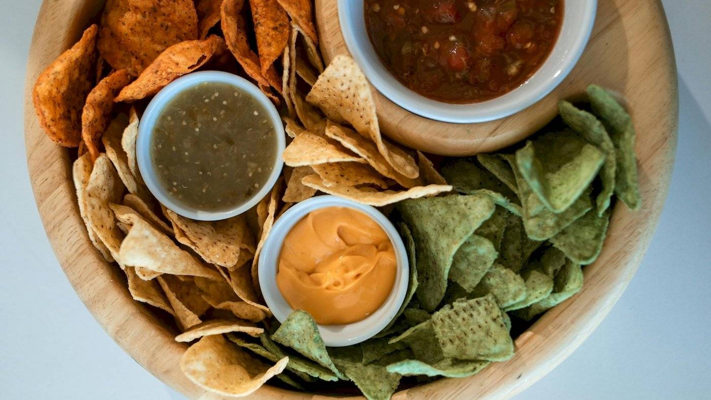 Eine Holzschale mit verschiedenen mexikanischen Chips und Saucen.