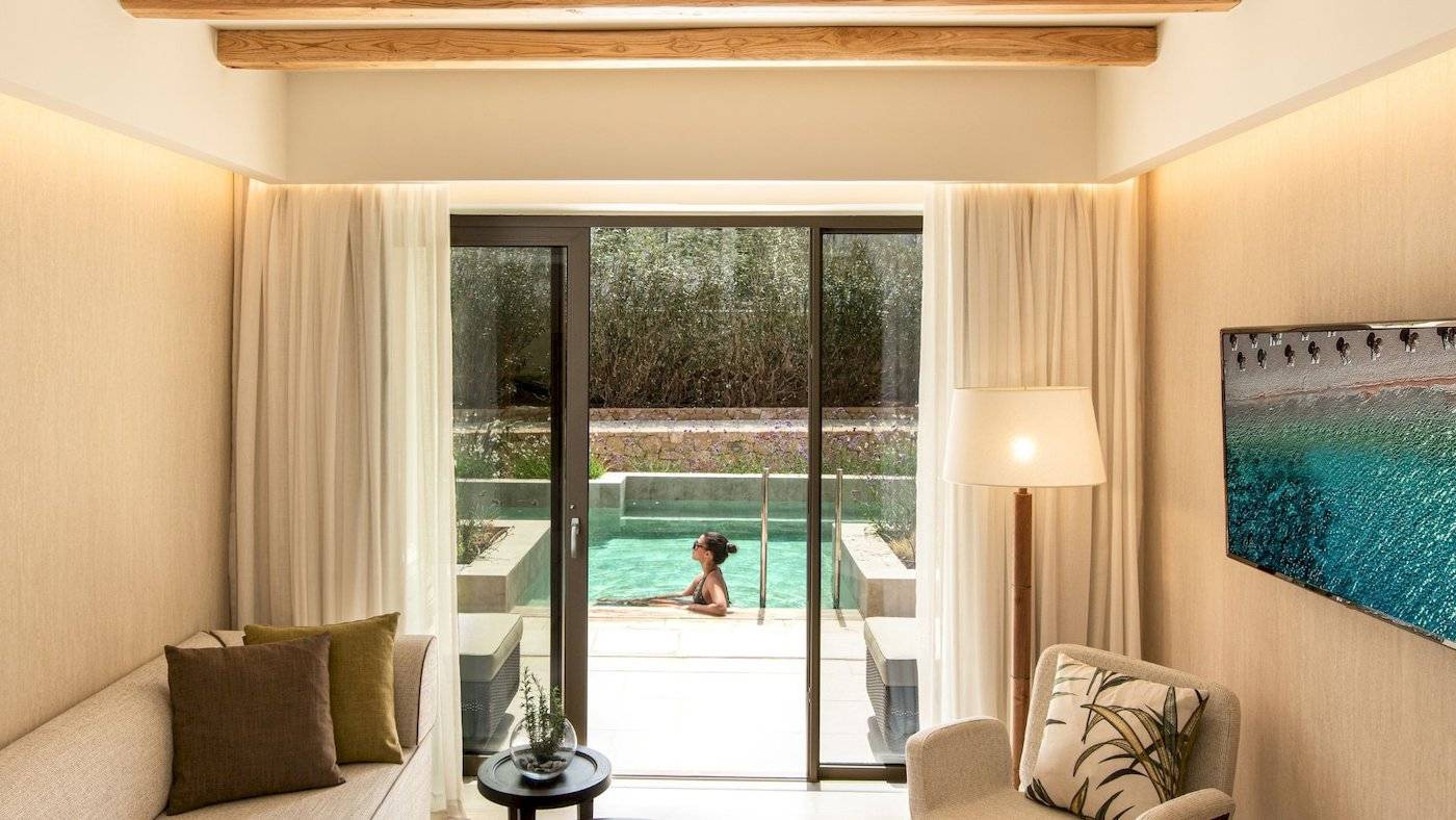 Wohnbereich im Mitsis Selection Rinela Hotel mit Blick auf den Poolbereich.