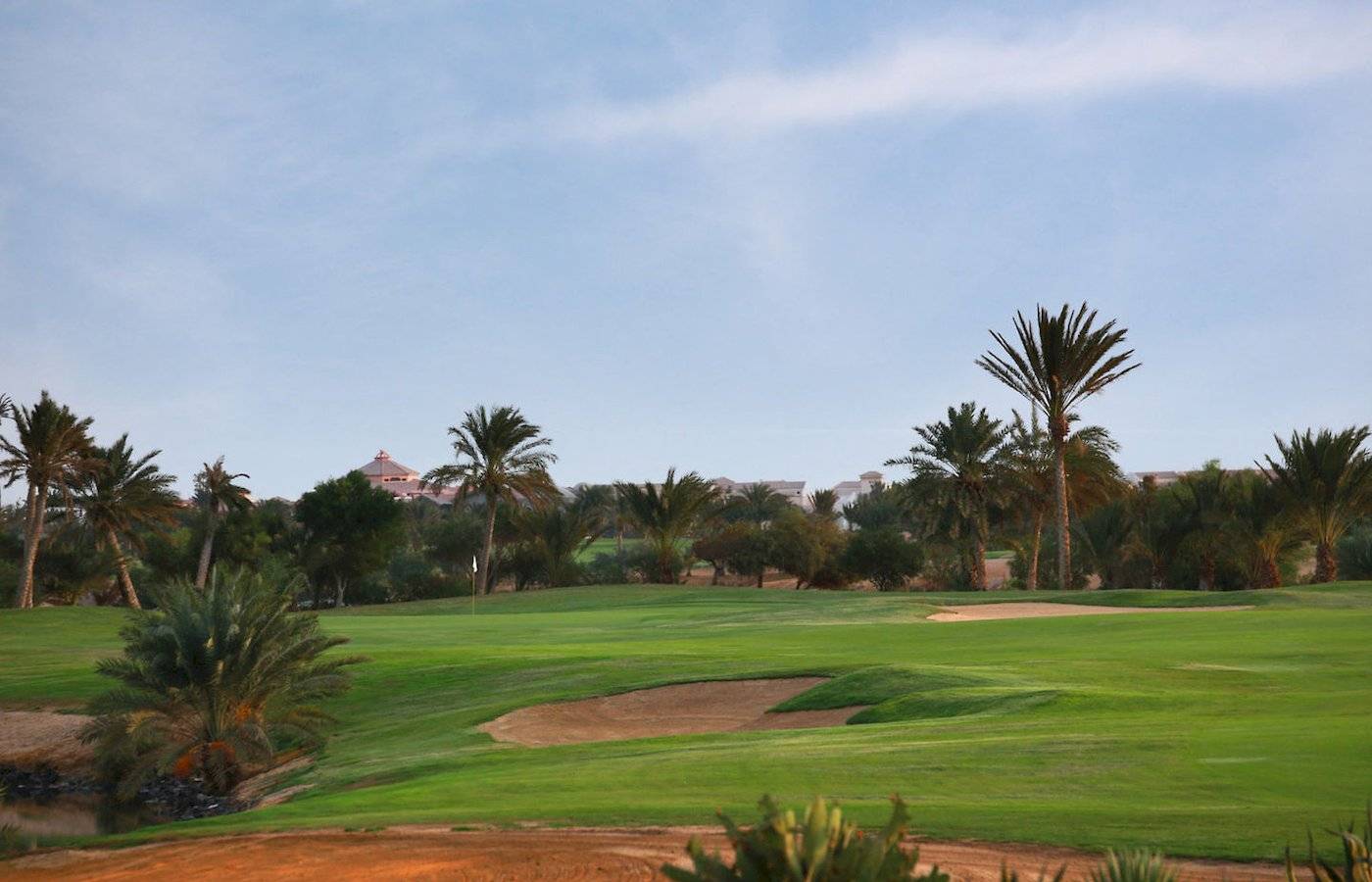 Golfplatz im Moevenpick Resort & Spa El Gouna mit gruenem Rasen und Palmen.