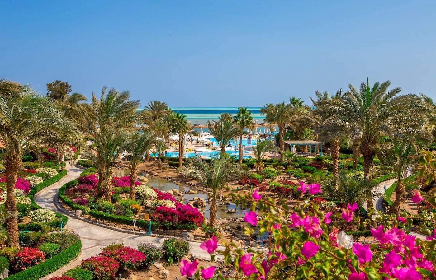 Außenbereich des Mövenpick Resort & Spa El Gouna mit Palmen, Blumen und Blick auf das Meer